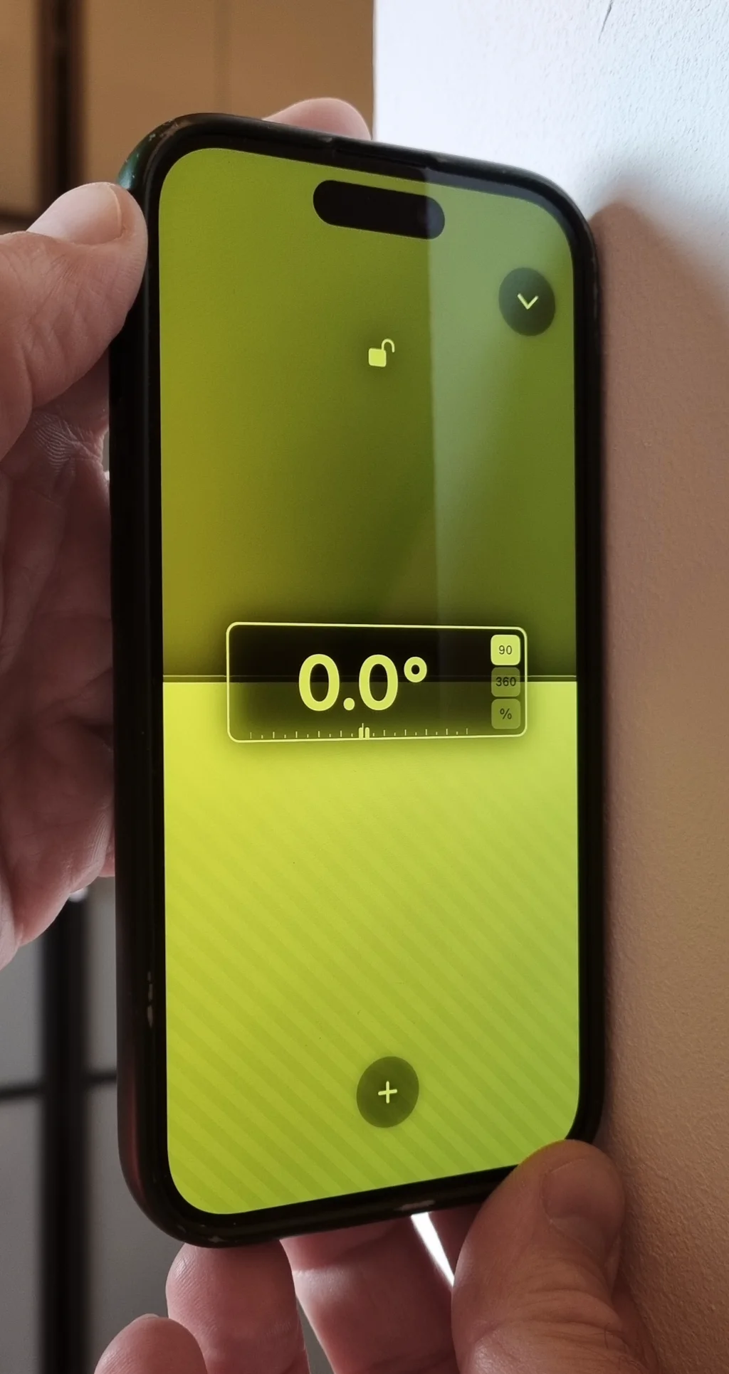 Handy wird an eine Wand gehalten und zeigt 0,0° im vertikalen Winkelmesser-Modus